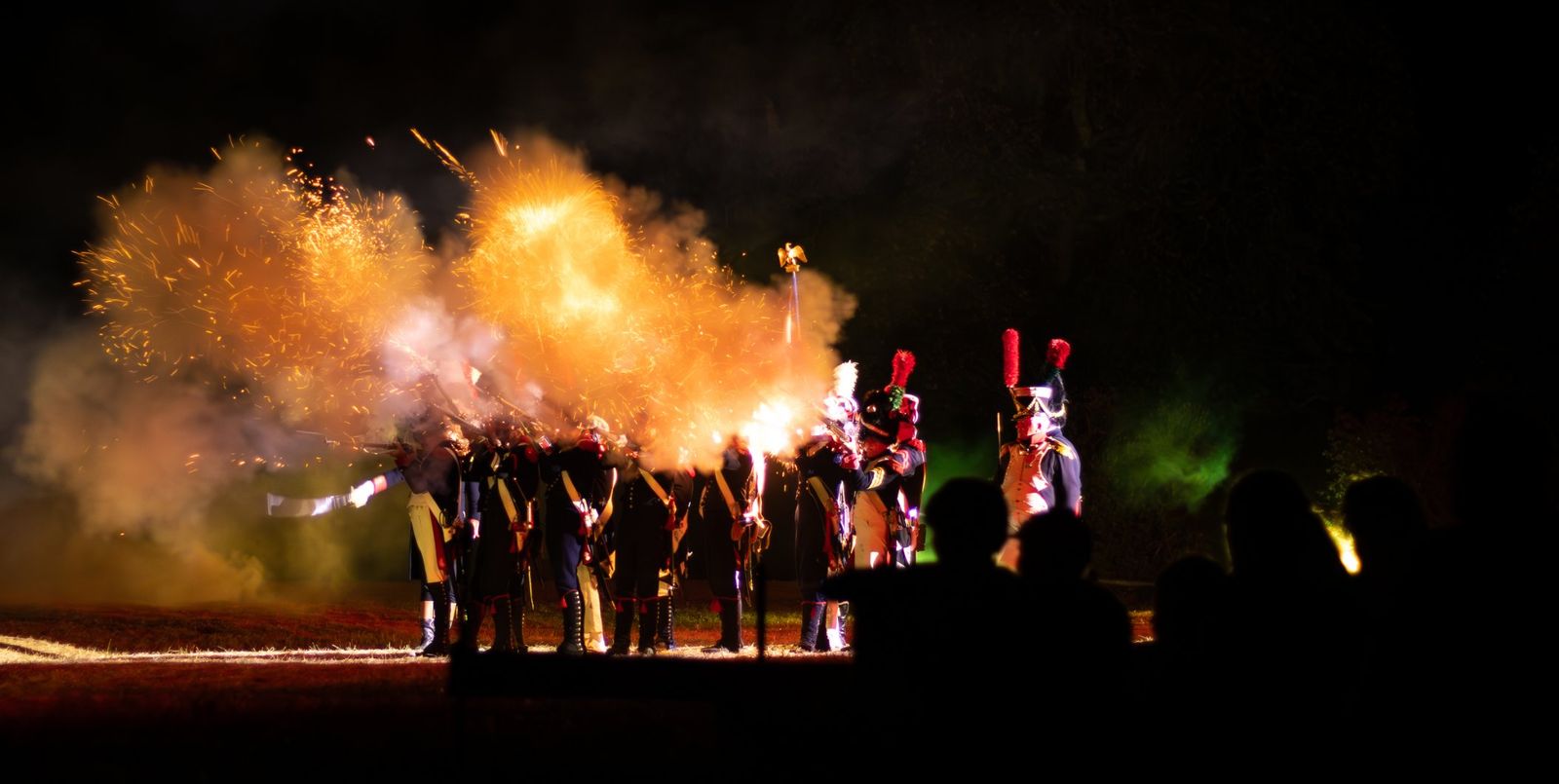 Une salve de mousquets projette des flammes et de la fumée dans la nuit